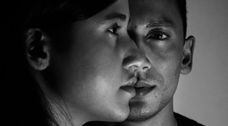 Artistic black and white portrait of a man and woman in dramatic lighting.