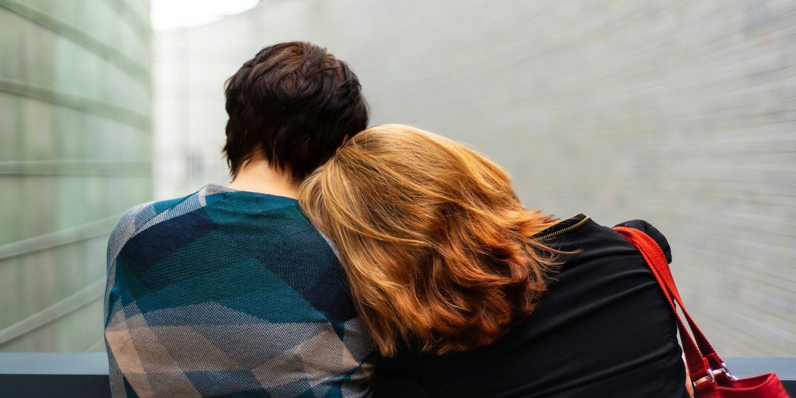 a woman rests her head on another person's shoulder